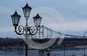 Lantern on river bank with bridge silhouette