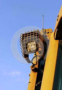 lantern, secure grille, on the roof of a bulldozer at construction site against the blue sky