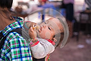 Lao Cai, Vietnam - Sep 7, 2017: Ethnic minority child on her mother back at local market in Y Ty, Bat Xat district