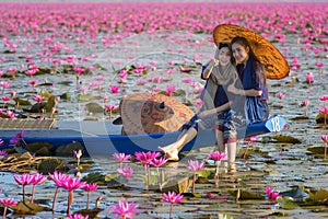 Laos woman sitting on the boat in flower lotus lake, Woman wearing traditional Thai people