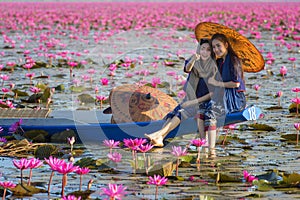 Laos woman sitting on the boat in flower lotus lake, Woman wearing traditional Thai people photo