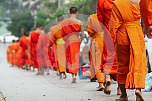 Laotian Buddhist monks walking along the street during alms giving ceremony in Luang Prabang, Laos
