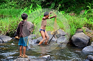 Laotian children fisher using fishing net catch fish in stream