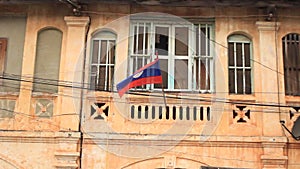 Laotian flag hanging from a deteriorating communist style home in Suvannakhet