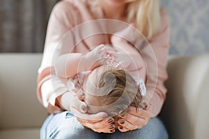 The mother supports the head of the baby lying on her lap