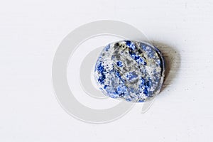 Lapis-lazuli polished tumbled stone pebble on a white background with empty space