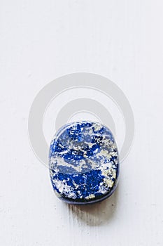 Lapis-lazuli polished tumbled stone pebble on a white background with empty space