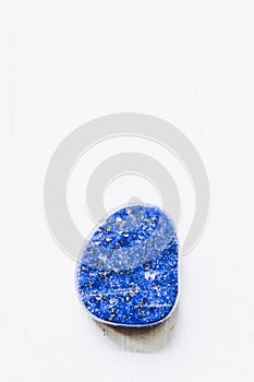 Lapis-lazuli polished tumbled stone pebble on a white background with empty space