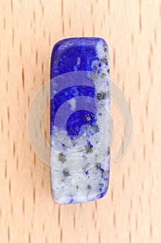 Lapis lazuli stone texture on light varnished wood background. Macro closeup