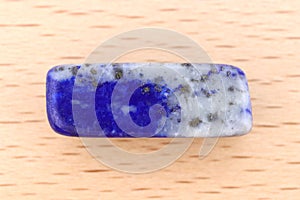 Lapis lazuli stone texture on light varnished wood background. Macro closeup
