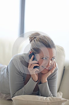 Lapping up the little luxuries in life. an attractive woman lounging on her couch while using the phone.