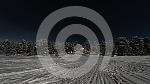 Lappish moonlit winter landscape, welcoming lights from the Hotel at the side of the frozen lake