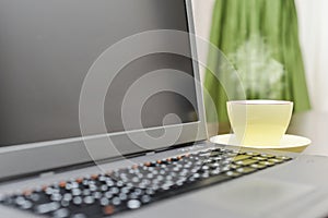 Laptop an address book, cup and pen on the table.