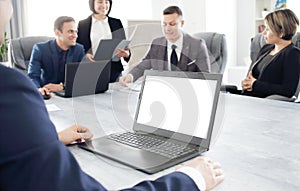 Laptop against the background of a group of young business people in the office discussing a work idea together