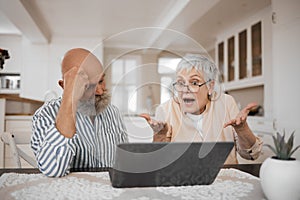 Laptop, argument and senior couple at their home for paying bills debt or mortgage online. Pension, technology and