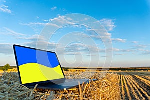 Laptop in the autumn field with Ukrainian flag