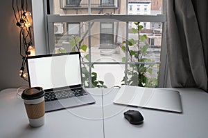 Laptop with blank screen and coffee cup on white table in office