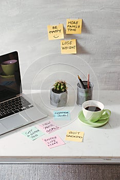 Laptop with blank screen and paper stickers and cup of coffee on tabletop