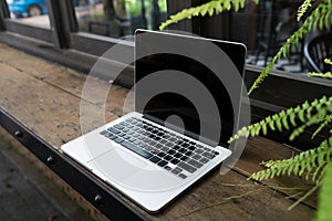 Laptop with blank screen on table, Coffee shop blurred background