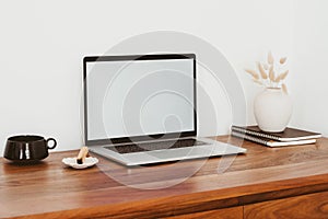 Laptop with blank screen on wooden table in home interior. Workplace mockup concept