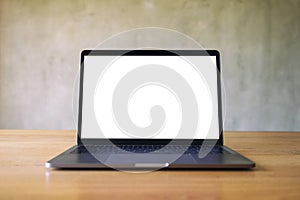 Laptop with blank white desktop screen on wooden table with concrete wall background