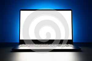 The laptop is on a blue background with a glowing white screen with copy space