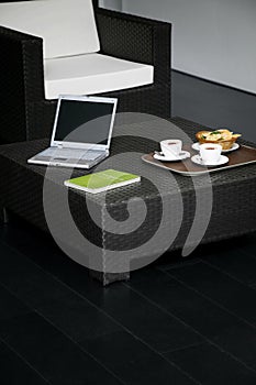 Laptop, book with some food and drink on the coffee table. Conceptual image