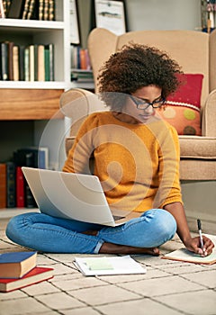 Laptop, books and African woman in library, floor and writing notes for education. Study, learning and female student