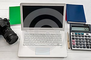 Laptop with calculator and digital camera at table