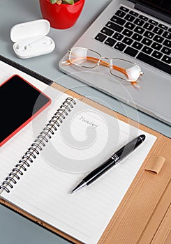 Laptop, cell phone and opened agenda on a grey desk close up