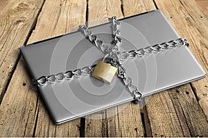 Laptop with chains and padlock on wooden