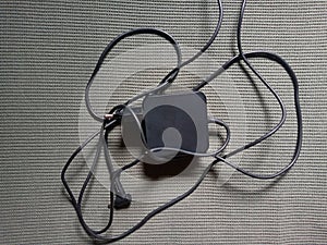 Laptop charger with its messy cable on a structured surface