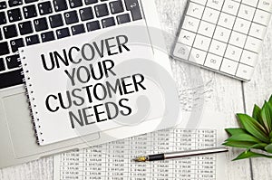 laptop charts, pen and a white notebook with the text uncover your customer needs