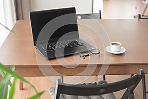 Laptop with coffee cup and glasses wooden table.