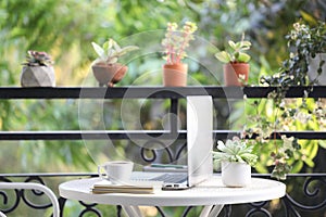 Laptop and coffee cup with notebooks on white table and brown plant pots