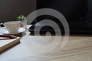 Laptop, coffee and flower on wood table at a workplace in the morning