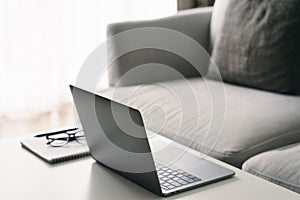 Laptop computer, ballpoint pen, notebook, and eyeglasses on the white coffee table in the living room, Working at home, Online