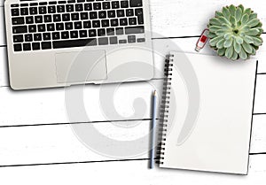 Laptop computer, blank notepad and pencil and succulent plant on rustic white wooden desk