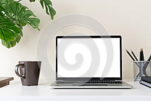 Laptop computer with blank screen for mockup on modern contemporary workspace desk with coffee cup and office supplies. Home