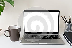 Laptop computer with blank screen for mockup on modern contemporary workspace desk with coffee cup and office supplies. Home