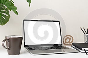 Laptop computer with blank screen for mockup on modern contemporary workspace desk with coffee cup and office supplies. Home