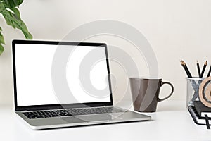 Laptop computer with blank screen for mockup on modern contemporary workspace desk with coffee cup and office supplies. Home