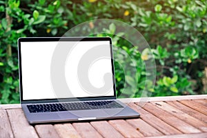 Laptop computer with blank white desktop screen on wooden table