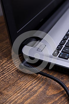 Laptop, computer is charging from a 220-volt outlet on a desk near the wall. Energy, accumulation. Mockup