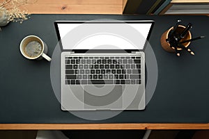 Laptop computer, cup of coffee and pencil holder on stylish workplace. Blank screen for your advertise text