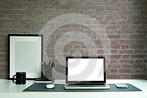 Laptop computer, digital tablet and houseplant on white table with brick wall