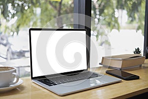 Laptop computer with empt display, smart phone, book and coffee cup on wooden table.