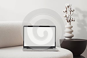 Laptop computer with empty blank mockup screen over white modern living room design.