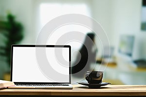 Laptop computer with empty screen and coffee cup on wooden table at home office.