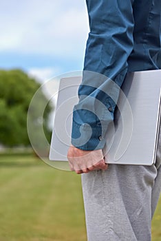 A laptop computer in the hand of a standing man